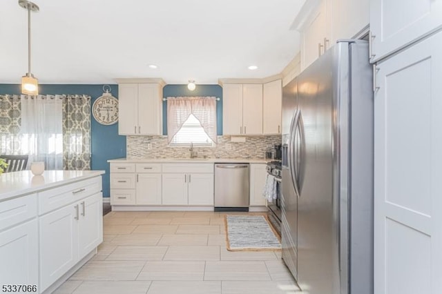 kitchen featuring tasteful backsplash, white cabinetry, sink, hanging light fixtures, and stainless steel appliances