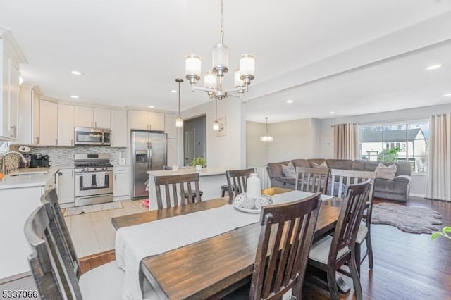 dining space with sink, an inviting chandelier, and light wood-type flooring