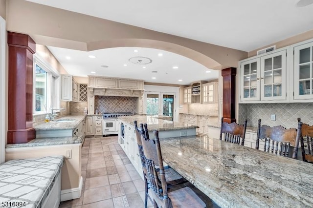 kitchen featuring white cabinetry, light stone countertops, a center island, and a kitchen bar