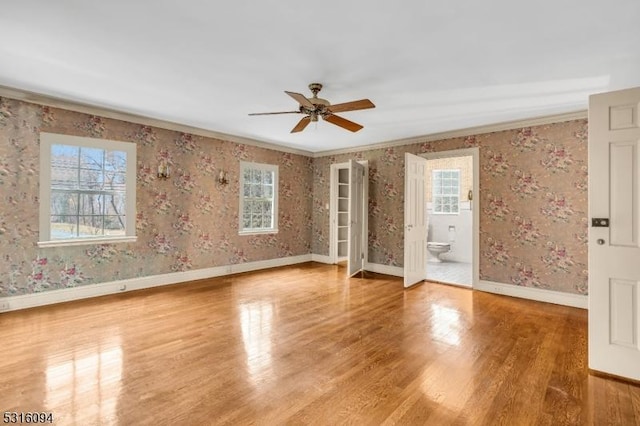 spare room with crown molding, wood-type flooring, and a wealth of natural light