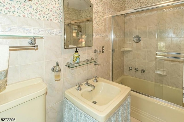 full bathroom with toilet, shower / bath combination with glass door, sink, and tile walls