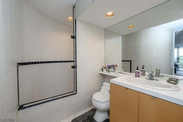 bathroom featuring vanity, toilet, and tile walls