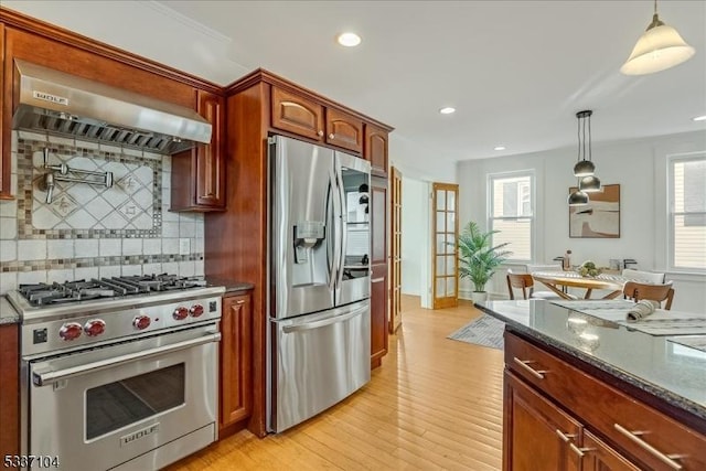 kitchen with dark stone counters, pendant lighting, stainless steel appliances, and exhaust hood