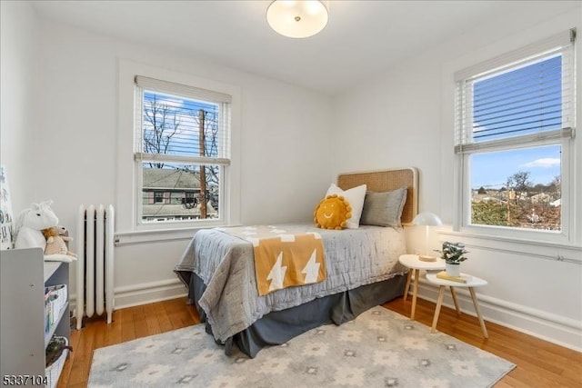 bedroom featuring baseboards, radiator heating unit, and wood finished floors