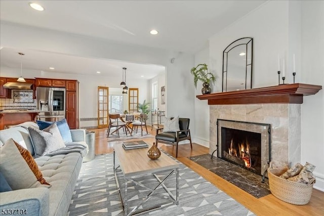 living room with baseboards, recessed lighting, a fireplace, and light wood-style floors