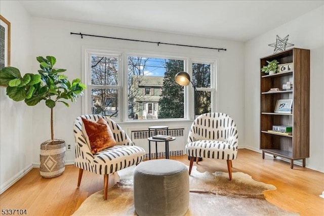 living area with a wealth of natural light, radiator heating unit, and wood finished floors