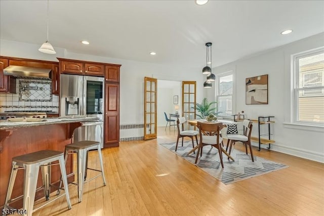 dining space featuring light wood finished floors, radiator heating unit, baseboards, and recessed lighting