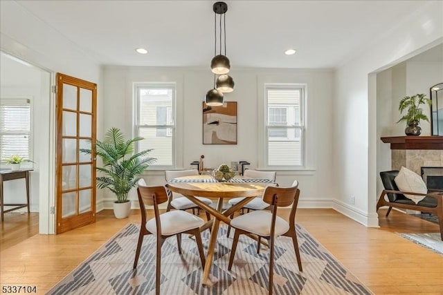 dining space with light wood finished floors, plenty of natural light, and a fireplace