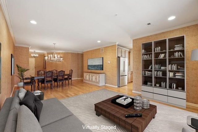 living room with an inviting chandelier, crown molding, and hardwood / wood-style flooring