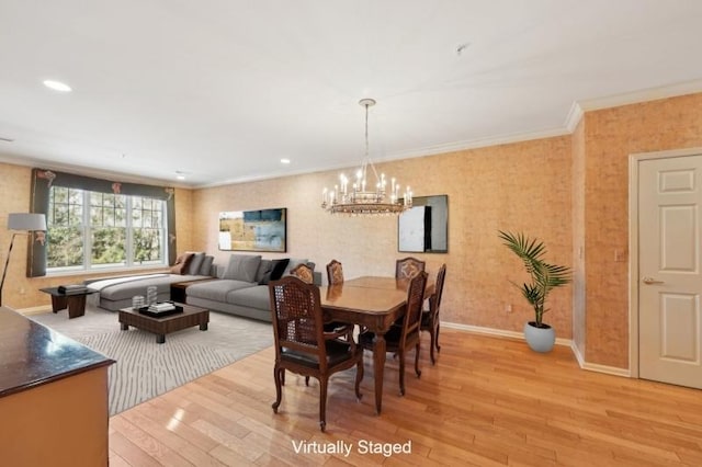 dining area with ornamental molding, a notable chandelier, and light hardwood / wood-style flooring