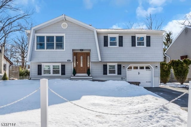 bi-level home with a garage, aphalt driveway, and a gambrel roof