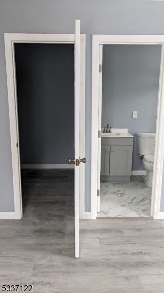 bathroom featuring toilet, baseboards, wood finished floors, and vanity