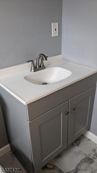 bathroom with marble finish floor, baseboards, and vanity