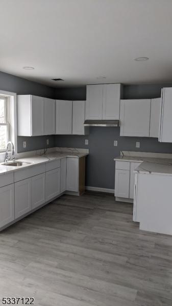 kitchen with sink, white cabinets, and light wood-type flooring