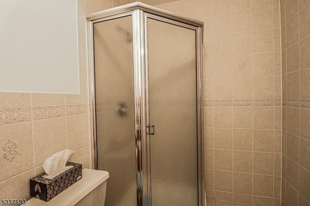 bathroom featuring walk in shower, tile walls, and toilet