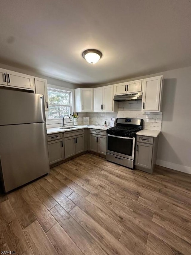 kitchen with tasteful backsplash, stainless steel appliances, light hardwood / wood-style floors, and sink