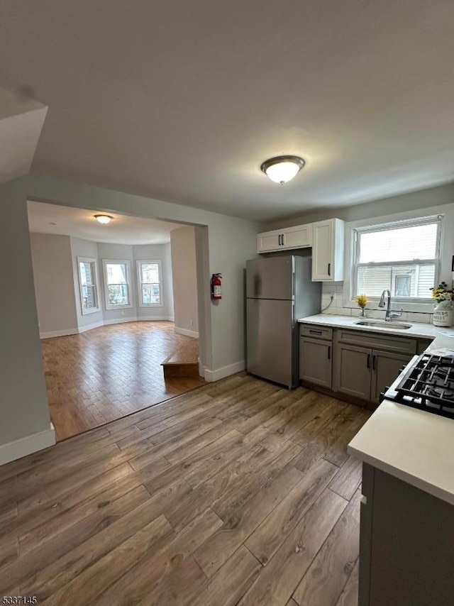 kitchen featuring stainless steel refrigerator, plenty of natural light, sink, and light hardwood / wood-style flooring