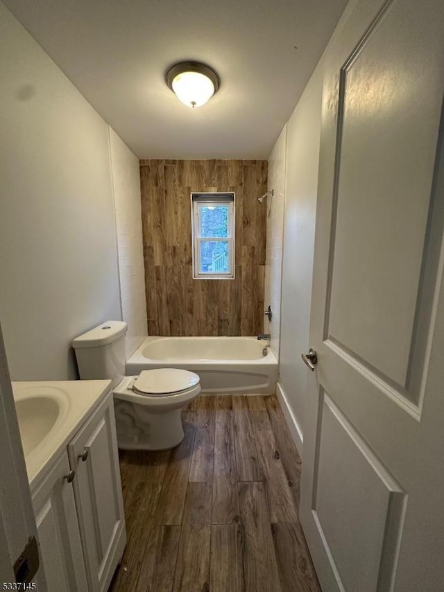 full bathroom with hardwood / wood-style flooring, tiled shower / bath, vanity, and toilet