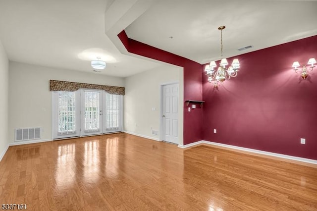 spare room featuring hardwood / wood-style floors and a notable chandelier