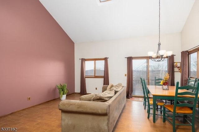 living room with high vaulted ceiling, light hardwood / wood-style floors, and a notable chandelier