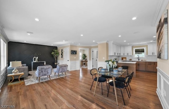 dining area with crown molding, sink, and light wood-type flooring