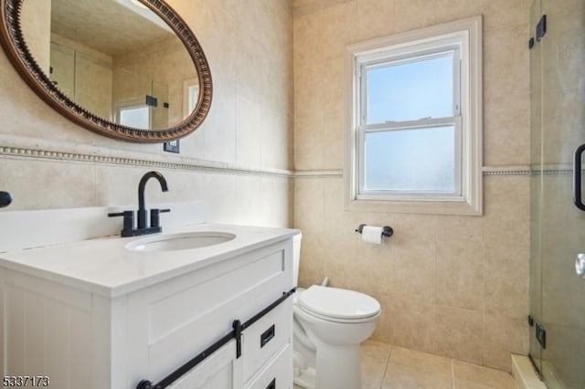 bathroom with tile walls, vanity, and a shower with door