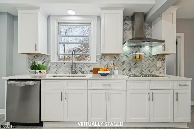 kitchen featuring sink, stainless steel dishwasher, white cabinets, and wall chimney exhaust hood