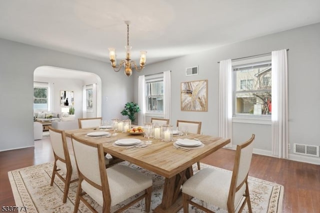 dining area with a notable chandelier and dark hardwood / wood-style flooring