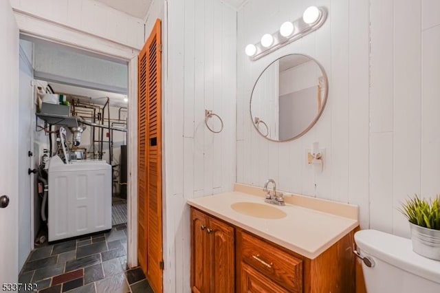 bathroom featuring vanity, toilet, and washer / dryer