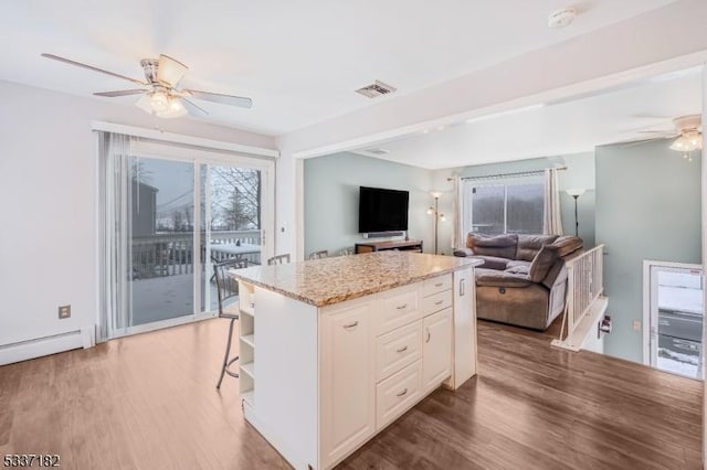 kitchen with white cabinetry, dark hardwood / wood-style flooring, ceiling fan, and a center island