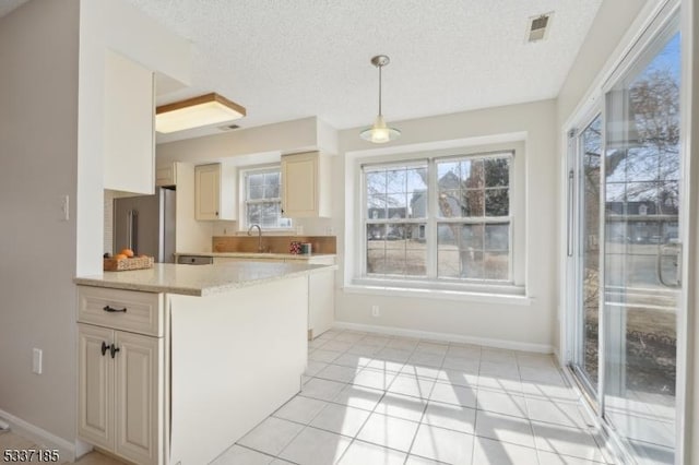 kitchen with visible vents, freestanding refrigerator, a sink, pendant lighting, and a textured ceiling