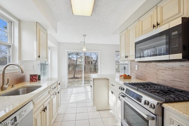 kitchen featuring a sink, cream cabinets, backsplash, stainless steel appliances, and light tile patterned flooring