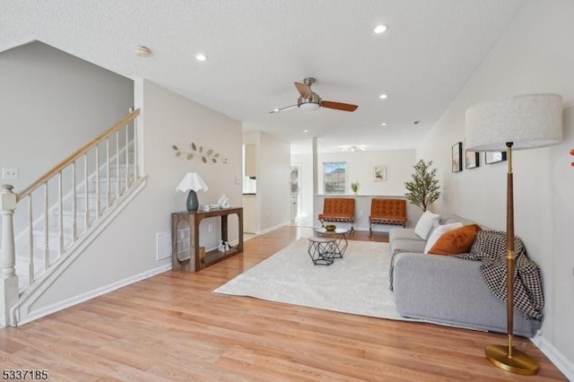 living room featuring stairway, baseboards, light wood-style flooring, recessed lighting, and ceiling fan