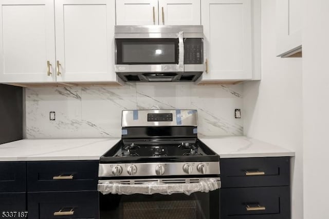 kitchen featuring white cabinetry, appliances with stainless steel finishes, light stone countertops, and backsplash