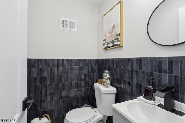 bathroom featuring vanity, tile walls, and toilet