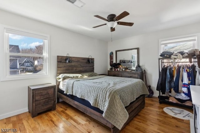 bedroom with multiple windows, ceiling fan, light wood-type flooring, and a closet