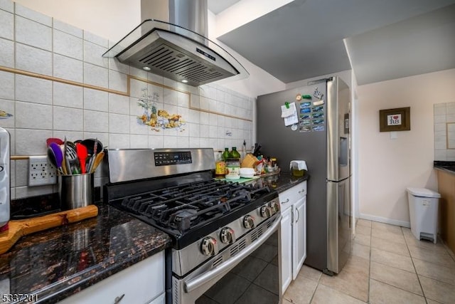 kitchen with appliances with stainless steel finishes, tasteful backsplash, white cabinetry, dark stone counters, and island exhaust hood