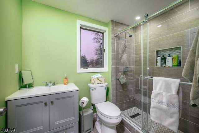 bathroom with walk in shower, vanity, and toilet