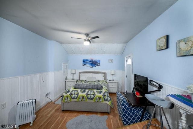 bedroom with vaulted ceiling, radiator heating unit, ceiling fan, and light wood-type flooring