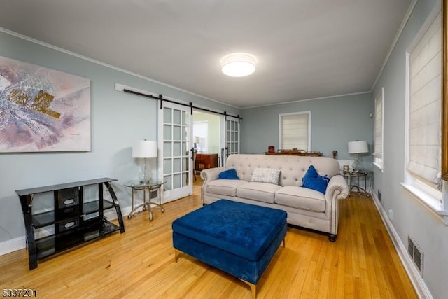 living room with hardwood / wood-style floors, crown molding, plenty of natural light, and a barn door