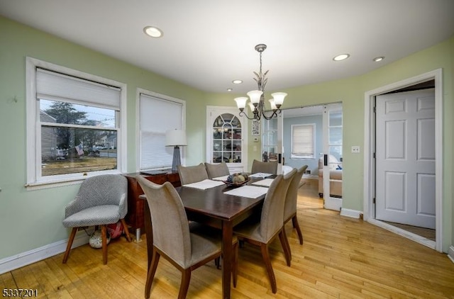 dining space with an inviting chandelier and light hardwood / wood-style flooring