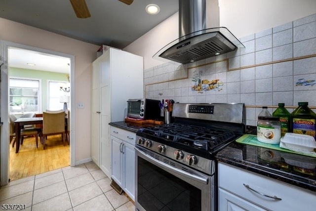 kitchen featuring light tile patterned floors, stainless steel range with gas cooktop, white cabinets, and island exhaust hood