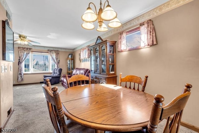 carpeted dining room featuring baseboards and ceiling fan with notable chandelier