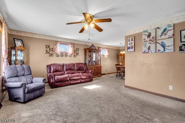 carpeted living area with baseboards and a ceiling fan