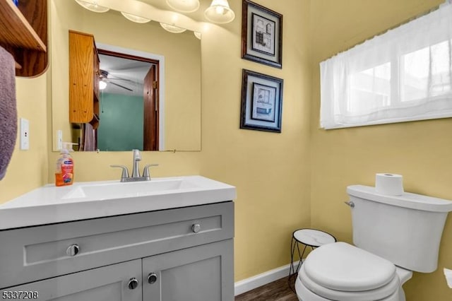 half bath featuring vanity, toilet, and baseboards