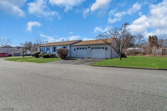 ranch-style home with aphalt driveway, an attached garage, and a front lawn