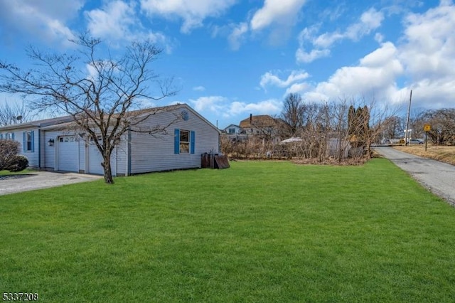 view of side of home featuring aphalt driveway, a yard, and a garage