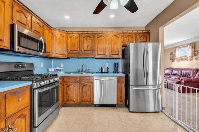 kitchen featuring brown cabinetry, stainless steel appliances, light countertops, and a sink