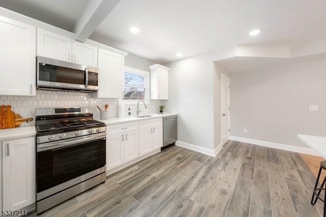 kitchen with white cabinetry, stainless steel appliances, light wood-type flooring, and backsplash