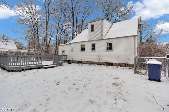 snow covered back of property with a wooden deck